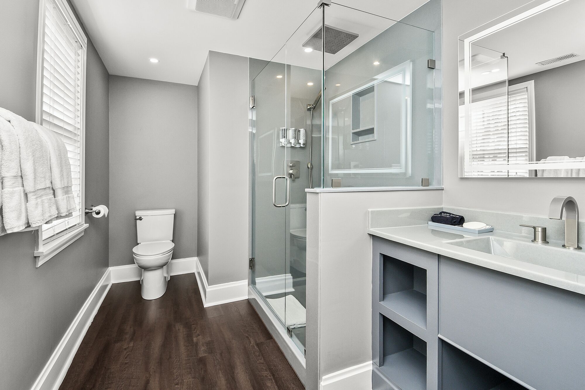 Une salle de bain moderne avec une douche à parois de verre, des toilettes blanches et un meuble-lavabo avec un miroir.