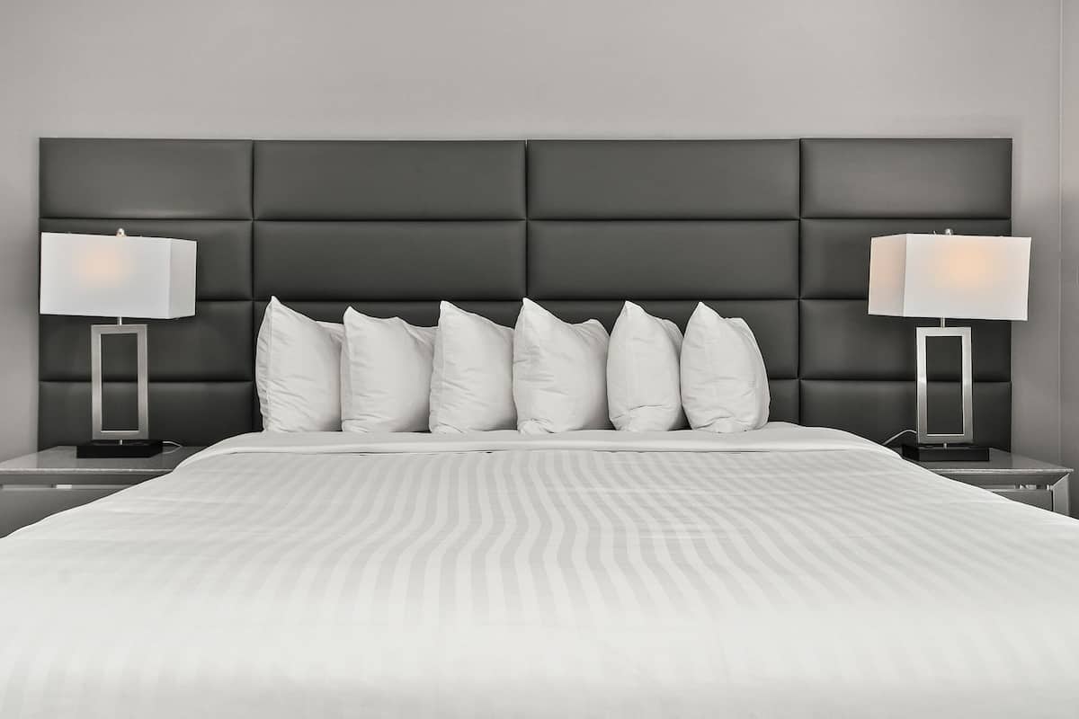 A modern hotel room with a large bed, a padded headboard, and two bedside lamps.