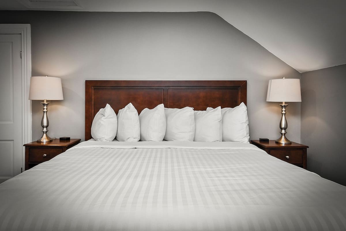 A neatly made bed with a wooden headboard, flanked by two bedside tables with lamps.