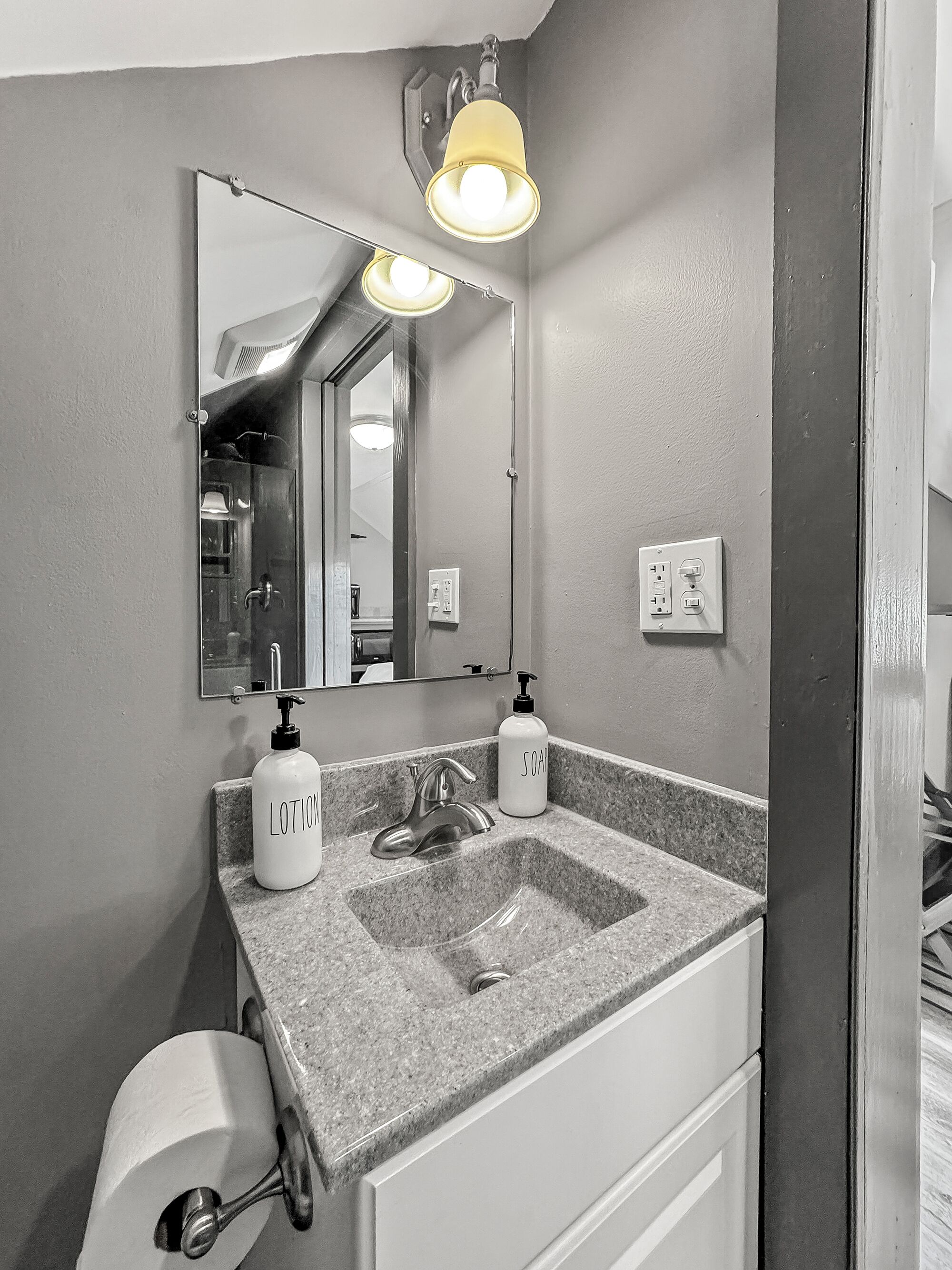 Une salle de bain avec un comptoir en granit, un lavabo, un miroir, un porte-serviettes et des toilettes.