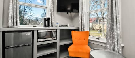 A compact kitchen with a microwave, coffee maker, and a flat-screen TV.