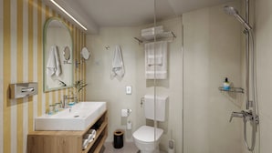 A modern bathroom with a wooden vanity, a toilet, a shower, and a mirror.