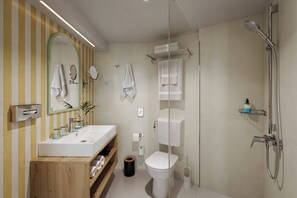 Un baño moderno con tocador de madera, inodoro, ducha y espejo.