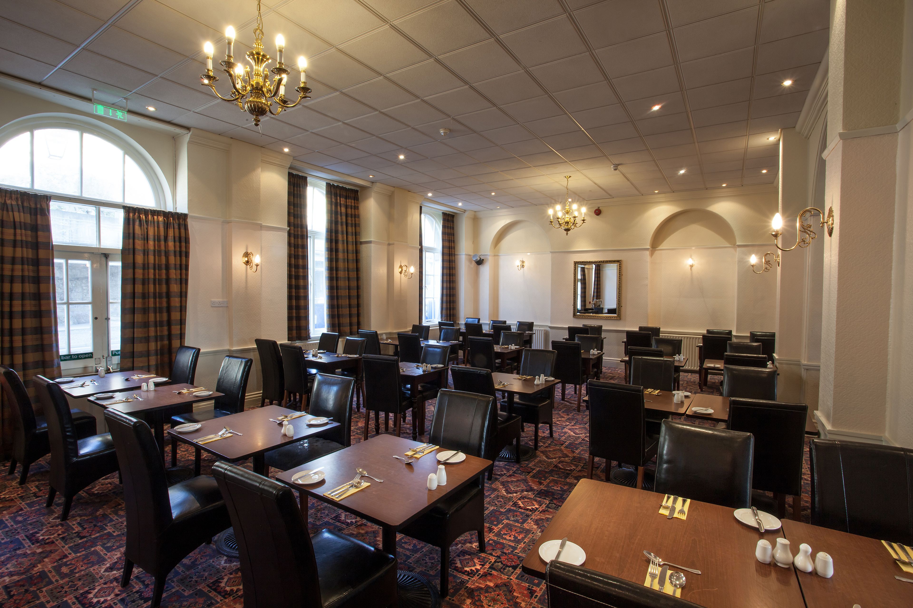 A conference room with tables and chairs, chandeliers, and large windows.