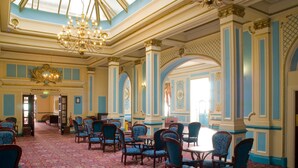 A grand room with blue and gold decor, featuring chandeliers, patterned carpet, and multiple seating areas. - The Metropole Hotel (Blackpool)