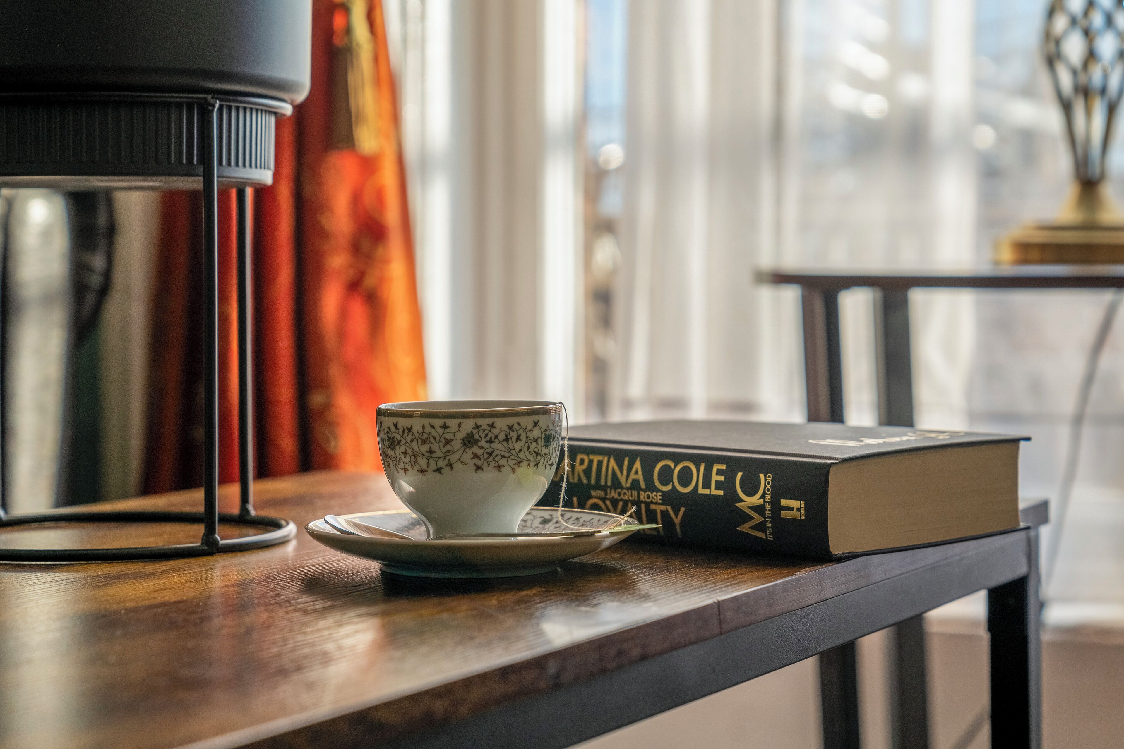 A table with a cup, saucer, and a book titled "Martina Cole UK".