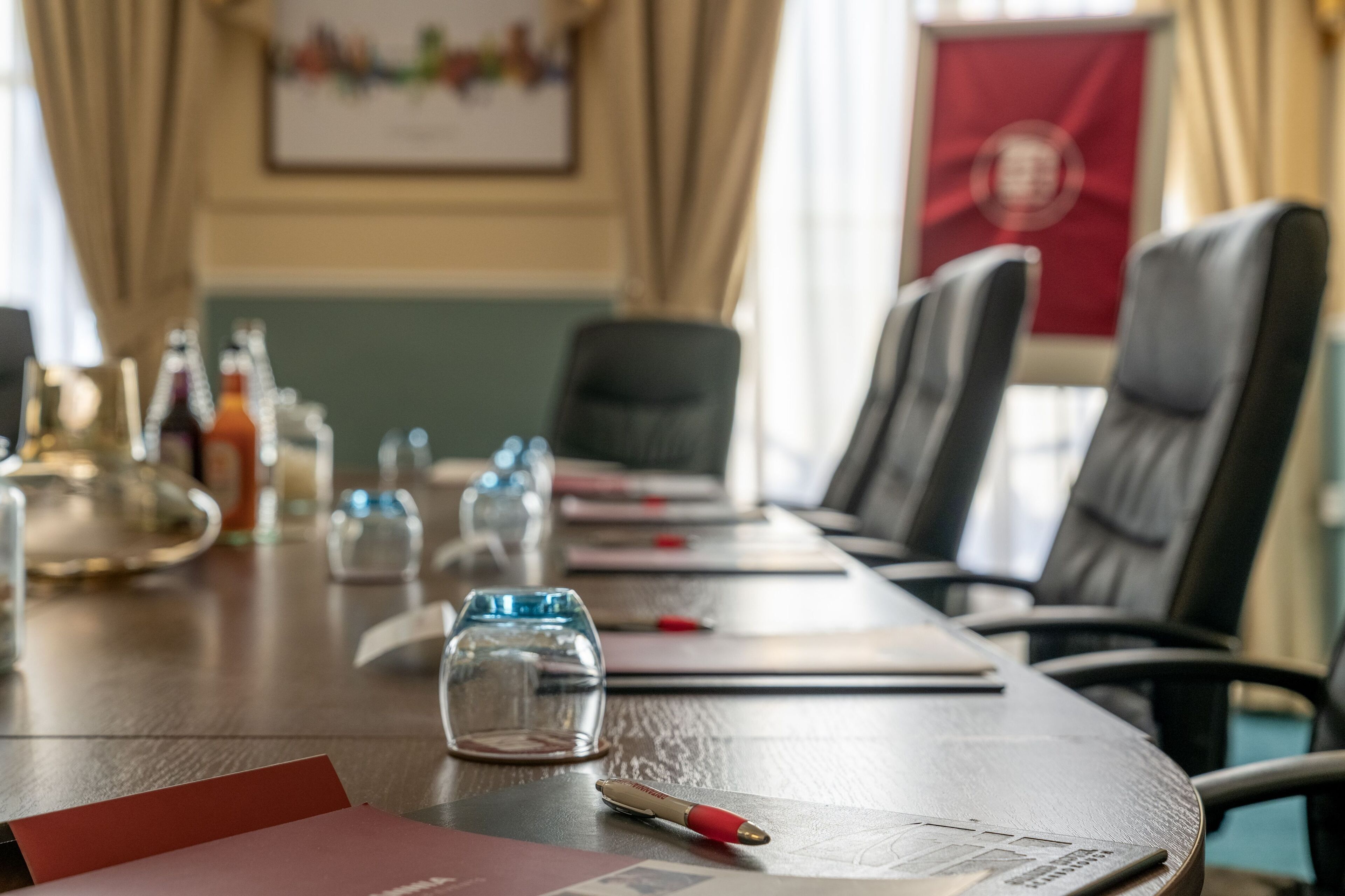 A conference room with a long table, chairs, and a few empty glasses.