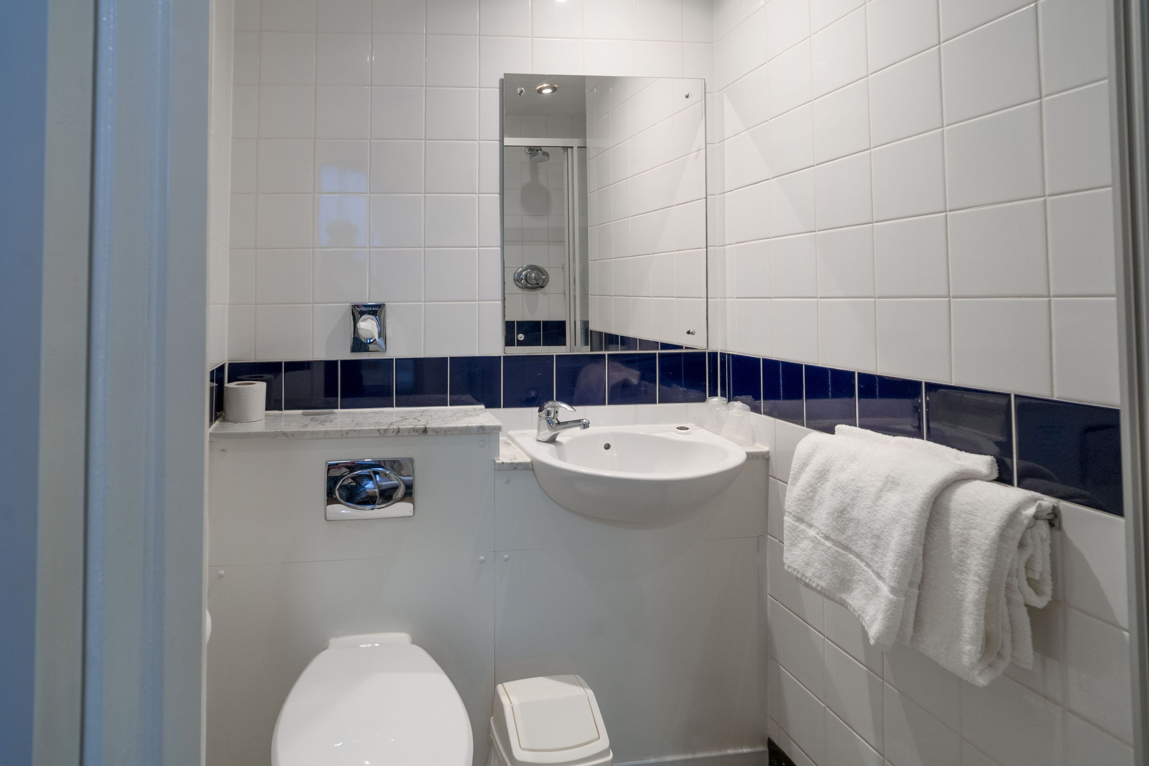 Un baño con inodoro, lavamanos y perchero para toallas.