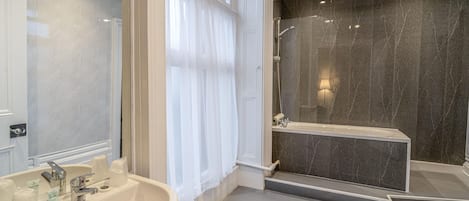 Un baño con un lavamanos grande, ducha y espejo.