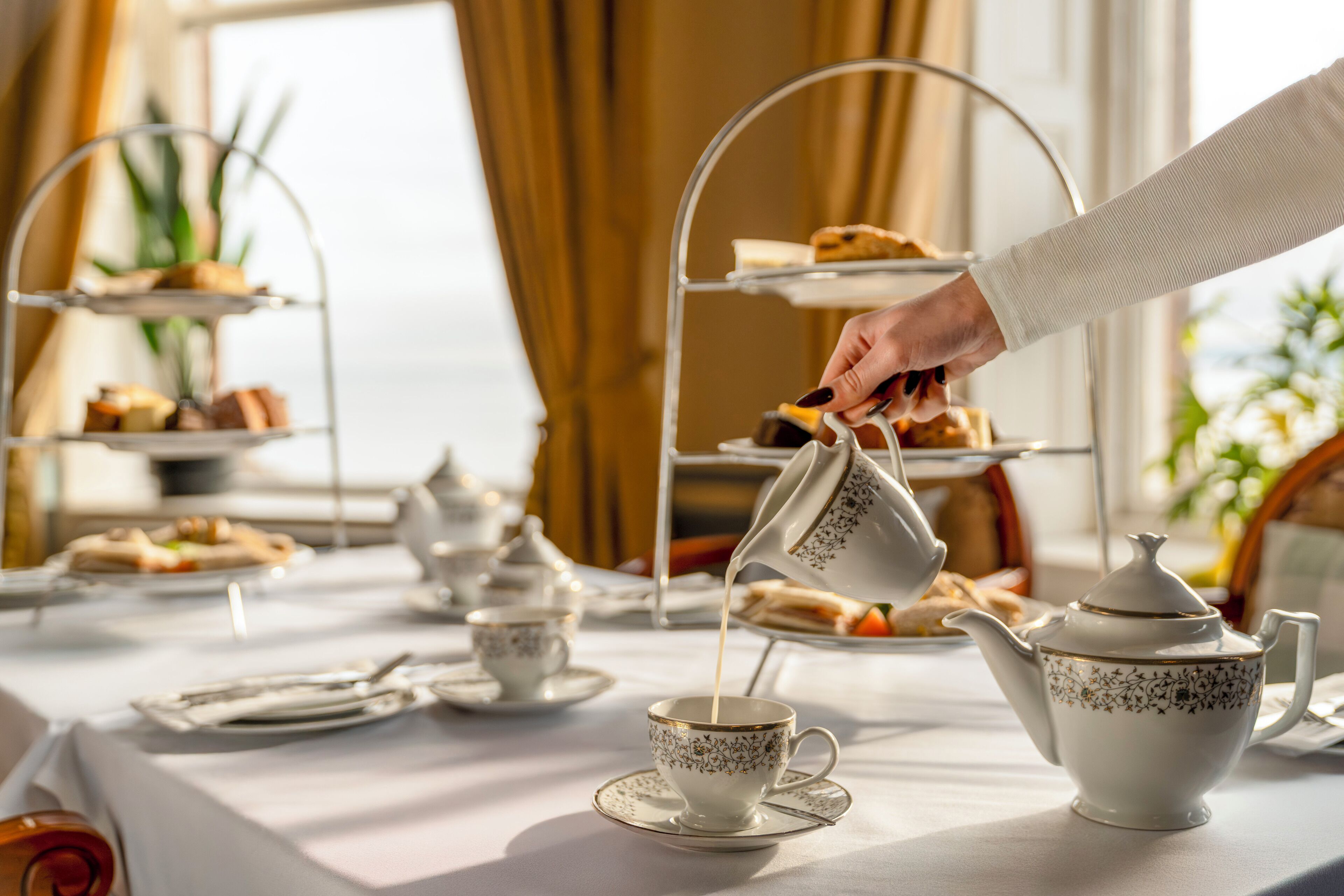 Un service à thé comprenant une théière, des tasses et un plateau de pâtisseries, le tout disposé sur une table.