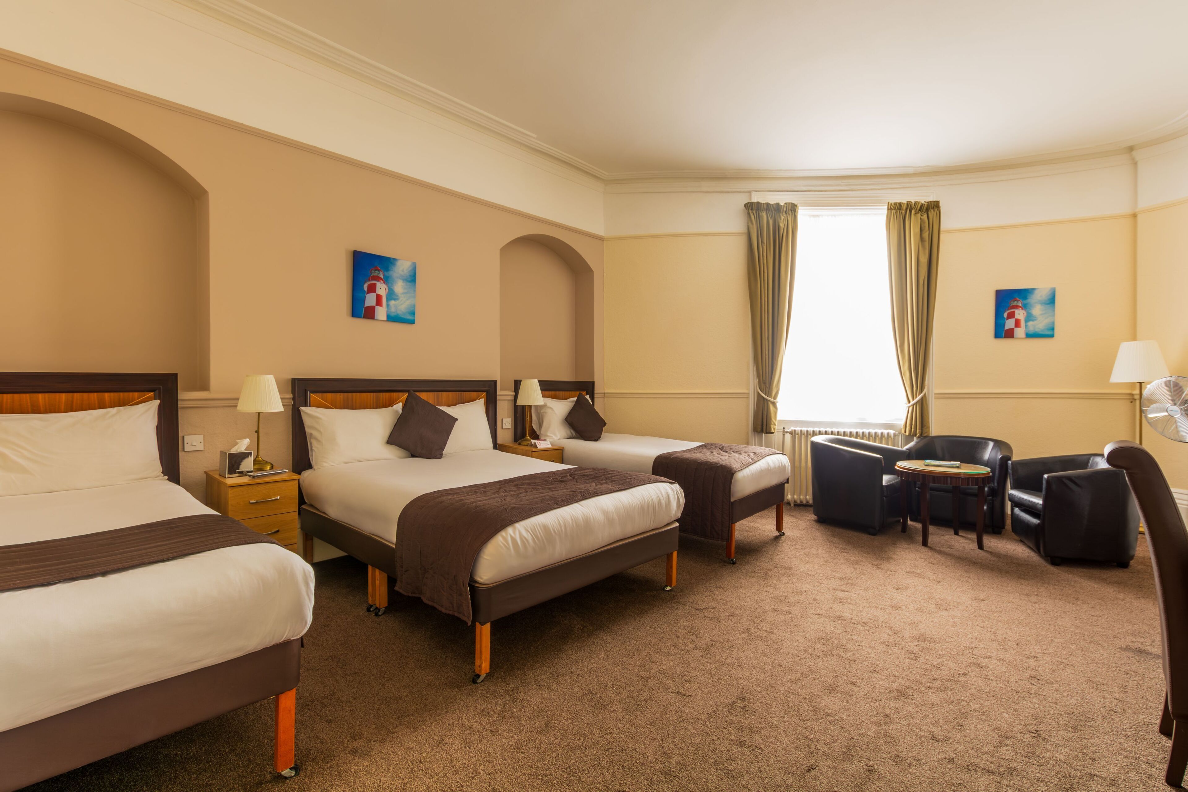 A hotel room with two beds, a desk, a chair, and a window with curtains.