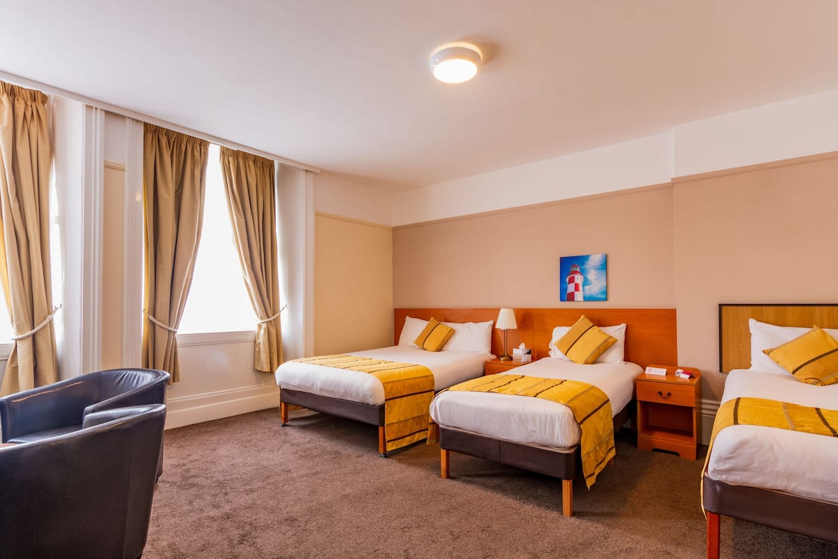 Une chambre d’hôtel avec deux lits, un bureau, une chaise et un tableau au mur.