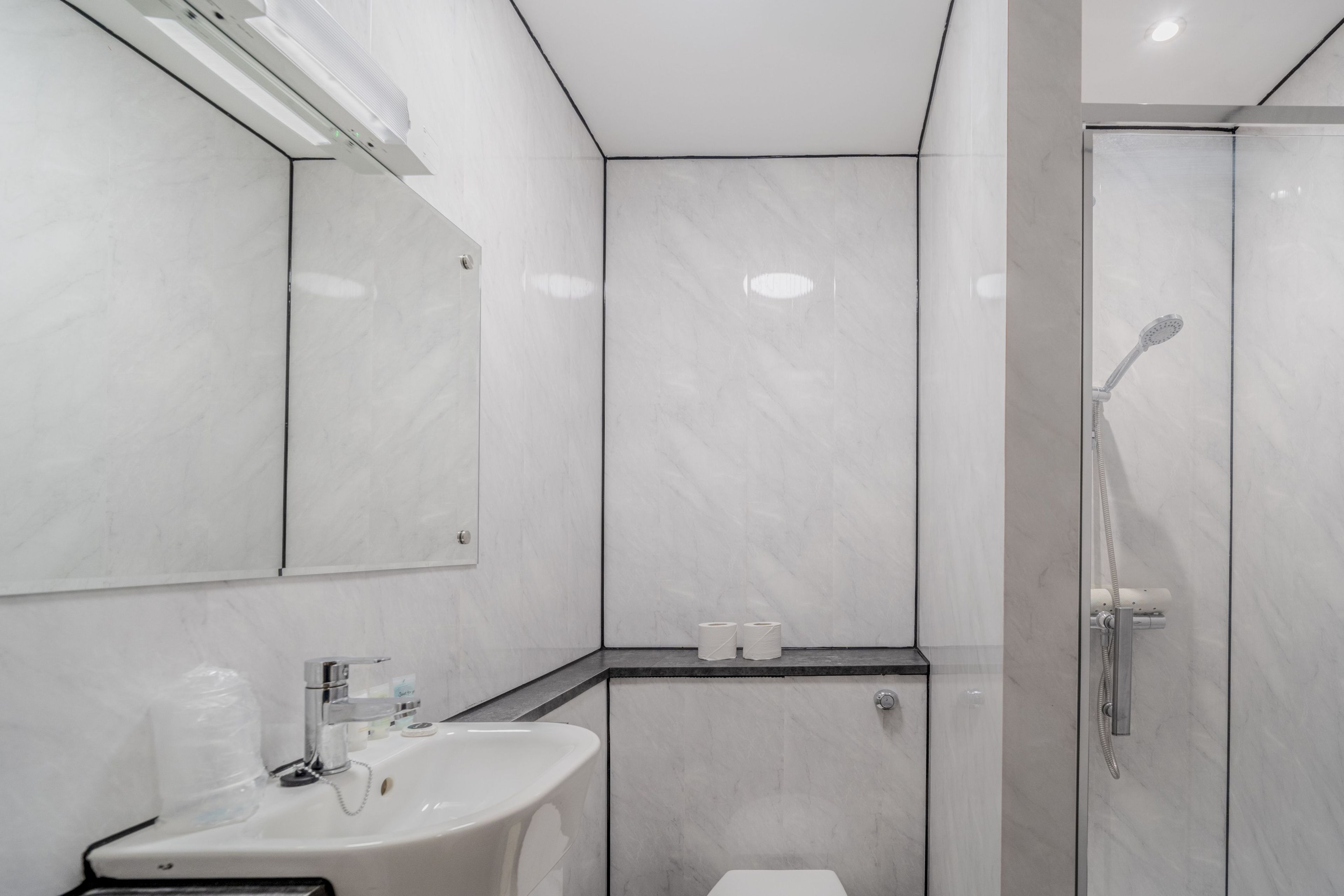 A modern bathroom with a sink, mirror, toilet, and shower.