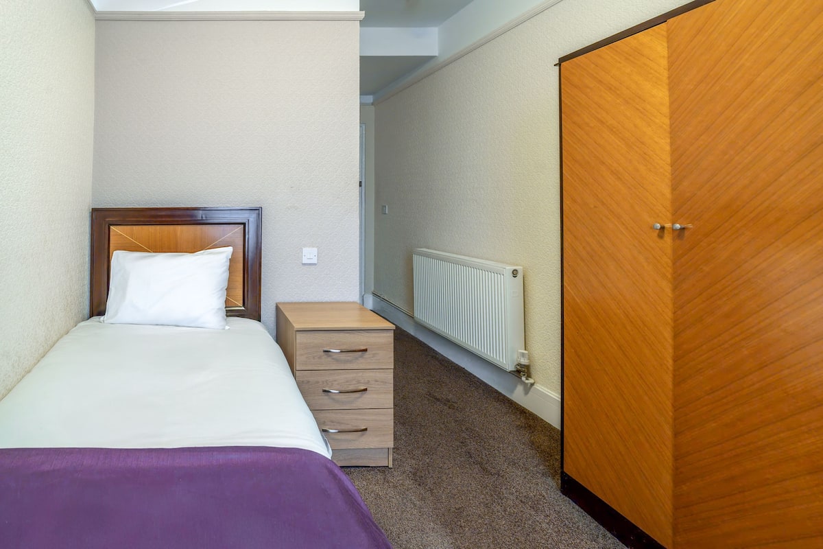 Une chambre à coucher comprenant un lit, une commode, un radiateur et une armoire.