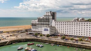 Un hotel amb diverses plantes, un senyal distintiu de 'Grand Burstin', una marina plena de vaixells i una platja al fons.