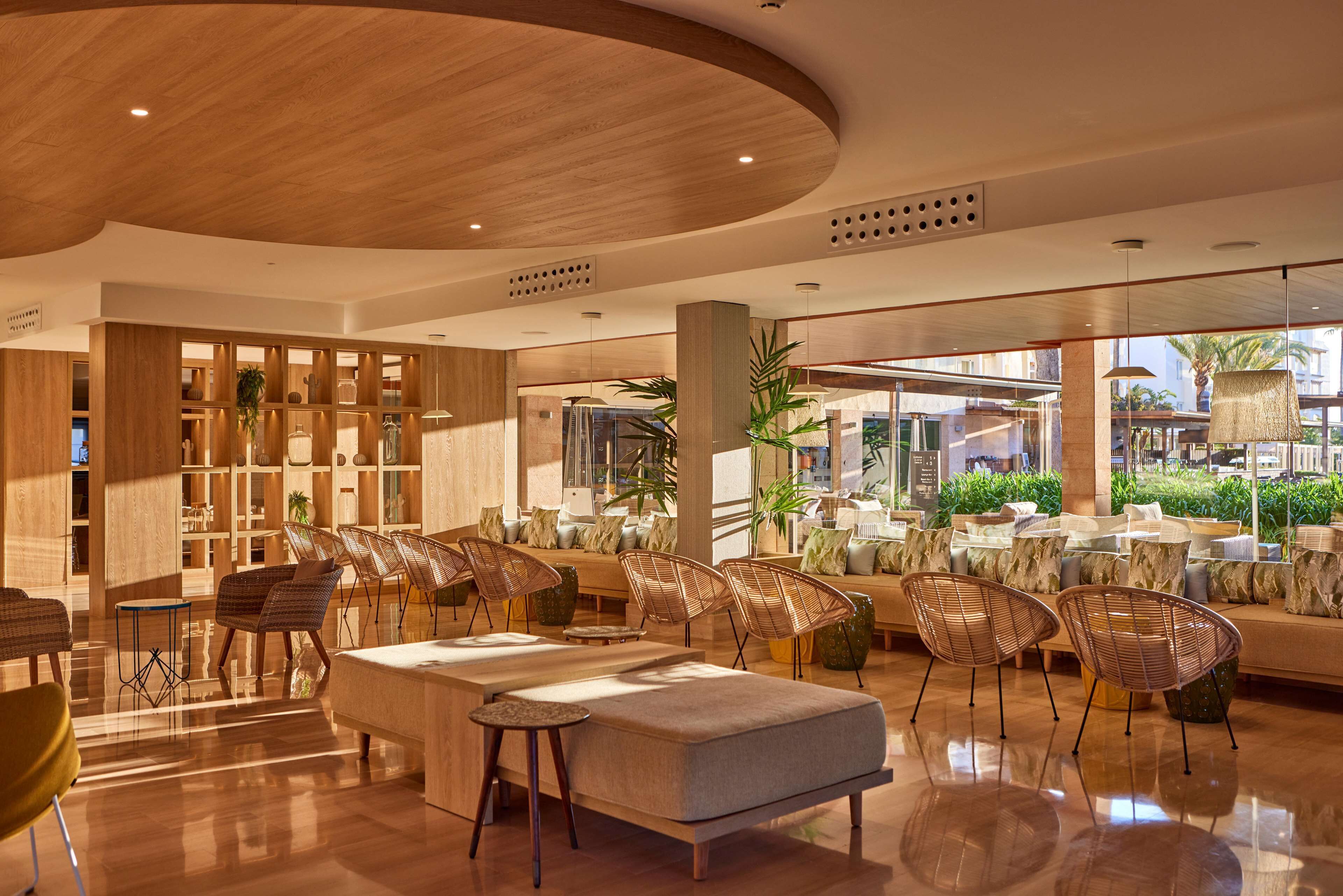 Eine moderne Lobby mit Holzboden, Sitzbereichen und großen Fenstern mit Blick ins Freie.