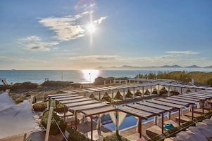 Un resort con zonas de estar al aire libre, piscina y vistas al mar y a las montañas.