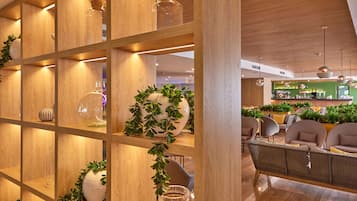 Ein modernes Interieur mit Holzböden, die Glasbehälter und Vasen zeigen, eine Sitzecke mit Sofas und eine Bar im Hintergrund.
