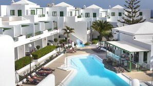 A resort with a swimming pool, sun loungers, and a covered outdoor seating area. - El Guarapo Apartamentos (Teguise)