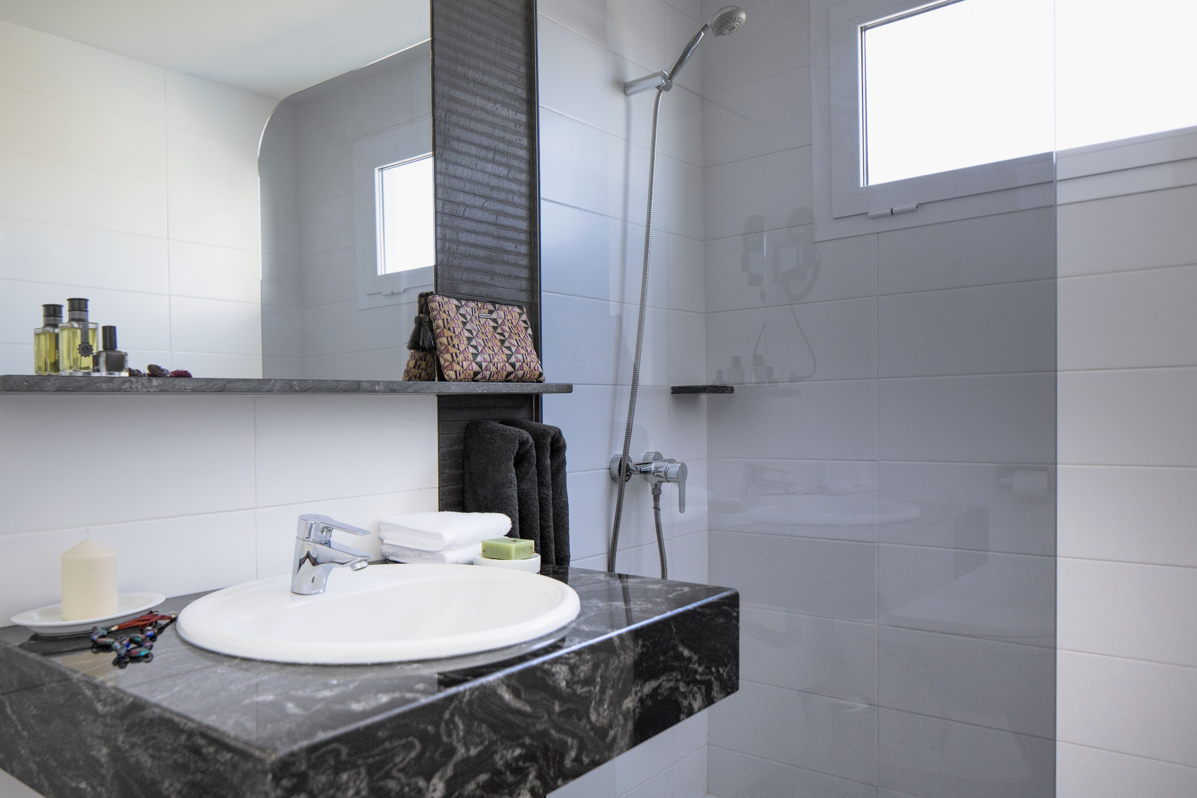 A modern bathroom with a white sink, black marble countertop, and a shower.