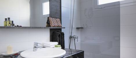 A modern bathroom with a white sink, black marble countertop, and a shower.