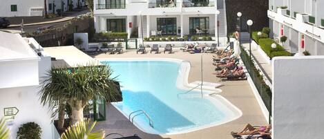 A resort with a swimming pool, multiple balconies, and a view of the mountains.