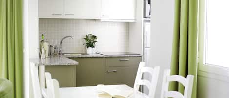 A modern kitchen with white cabinets, a countertop, and a dining table with chairs.