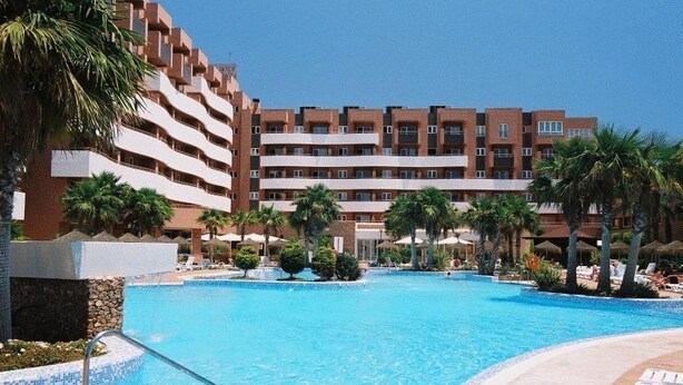 Un hotel con piscina, palmeras y un edificio de varios pisos.