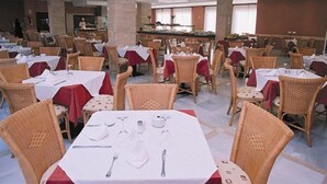 Un comedor con varias mesas y sillas, algunas con manteles rojos.