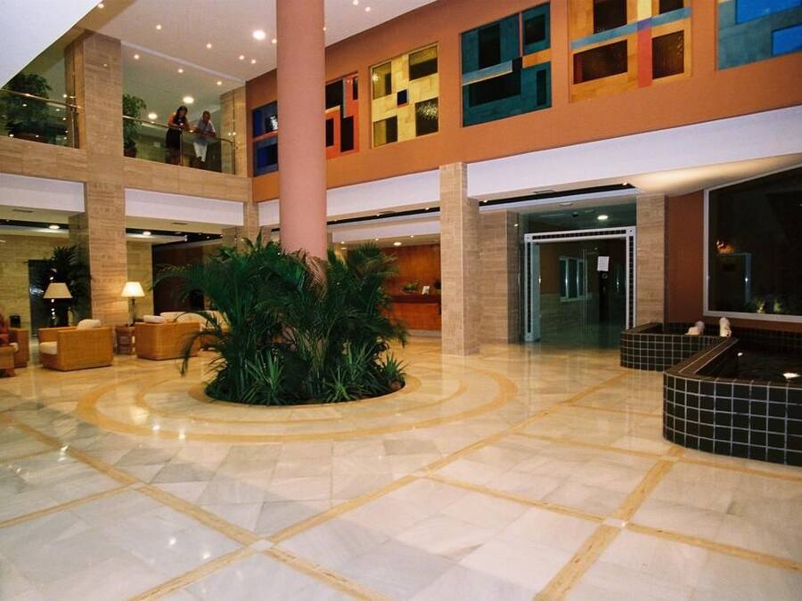 Un hall amplio con una fuente central, varias zonas de estar y un techo alto con luz natural.