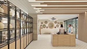 Ett modernt receptionsområde med en receptionsdisk i trä, en glasvägg och en vägg dekorerad med runda speglar och väggkonst.
