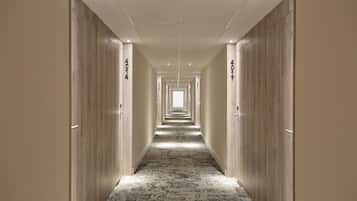 A long, narrow hallway with wooden doors on both sides, each labeled with numbers.