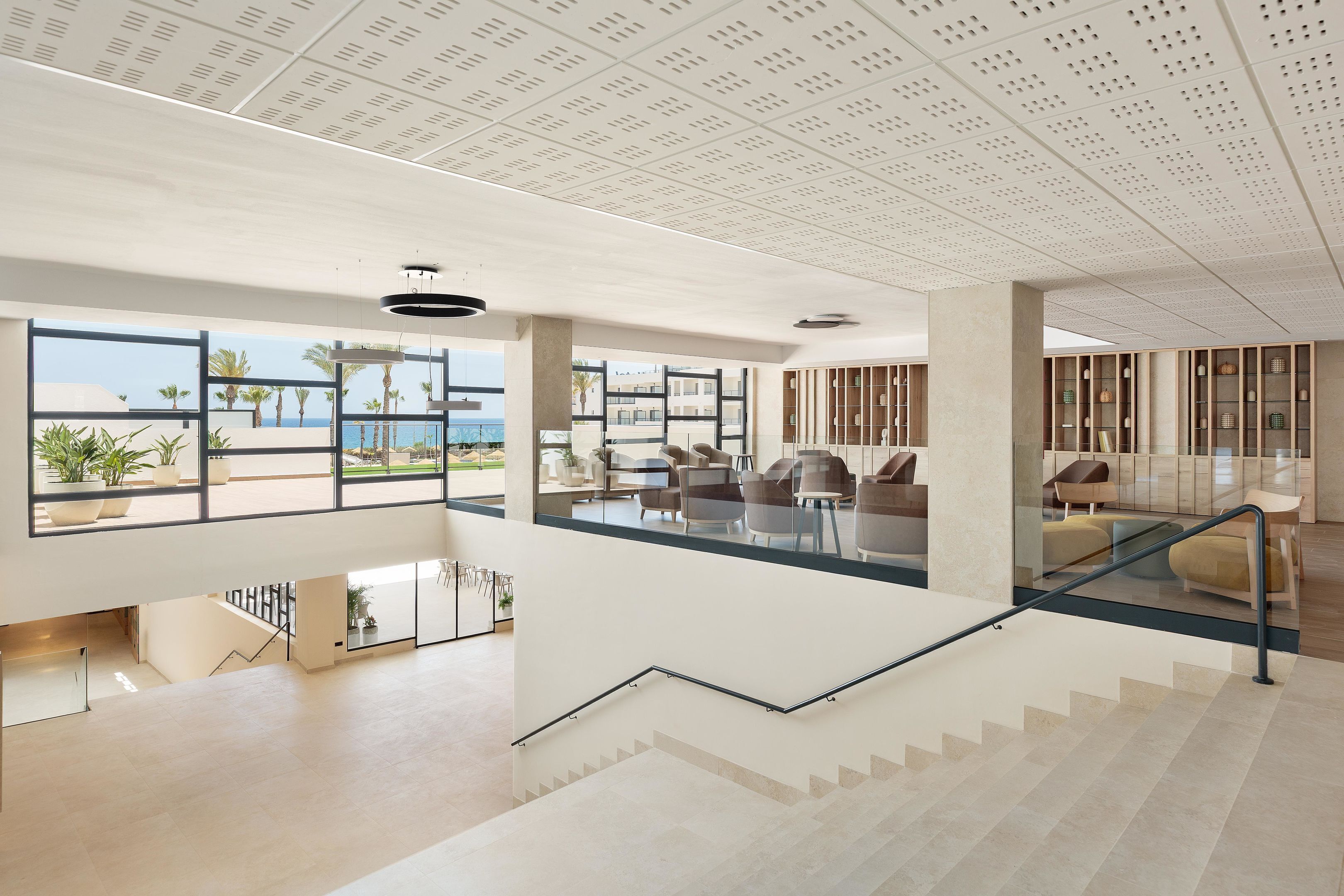 A spacious lobby with a staircase, large windows, and seating areas.