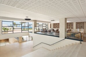 Un vestíbulo amplio con escaleras, ventanas grandes y zonas de descanso.