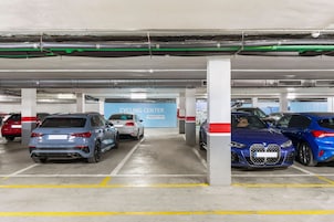 Een meerlaagse parkeergarage met verschillende geparkeerde auto's, waaronder een Audi en een BMW.