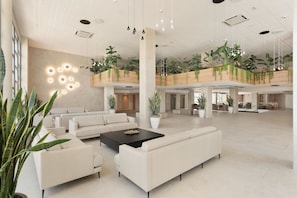 A spacious lobby with high ceilings, multiple seating areas, and indoor plants. - Hotel Best Oasis Tropical (Mojacar)