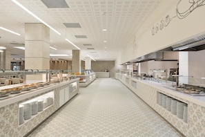 A spacious buffet area with multiple serving stations, a patterned floor, and a high ceiling with perforated panels. - Hotel Best Oasis Tropical (Mojacar)