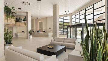Un hall amplio con muebles modernos, ventanas grandes y plantas de interior.