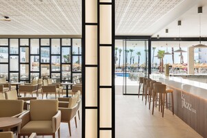 Un espace bar moderne avec vue sur la piscine, comprenant un comptoir, des sièges et de grandes fenêtres.