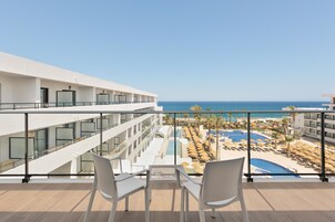 A hotel balcony with a view of a pool and beach.
