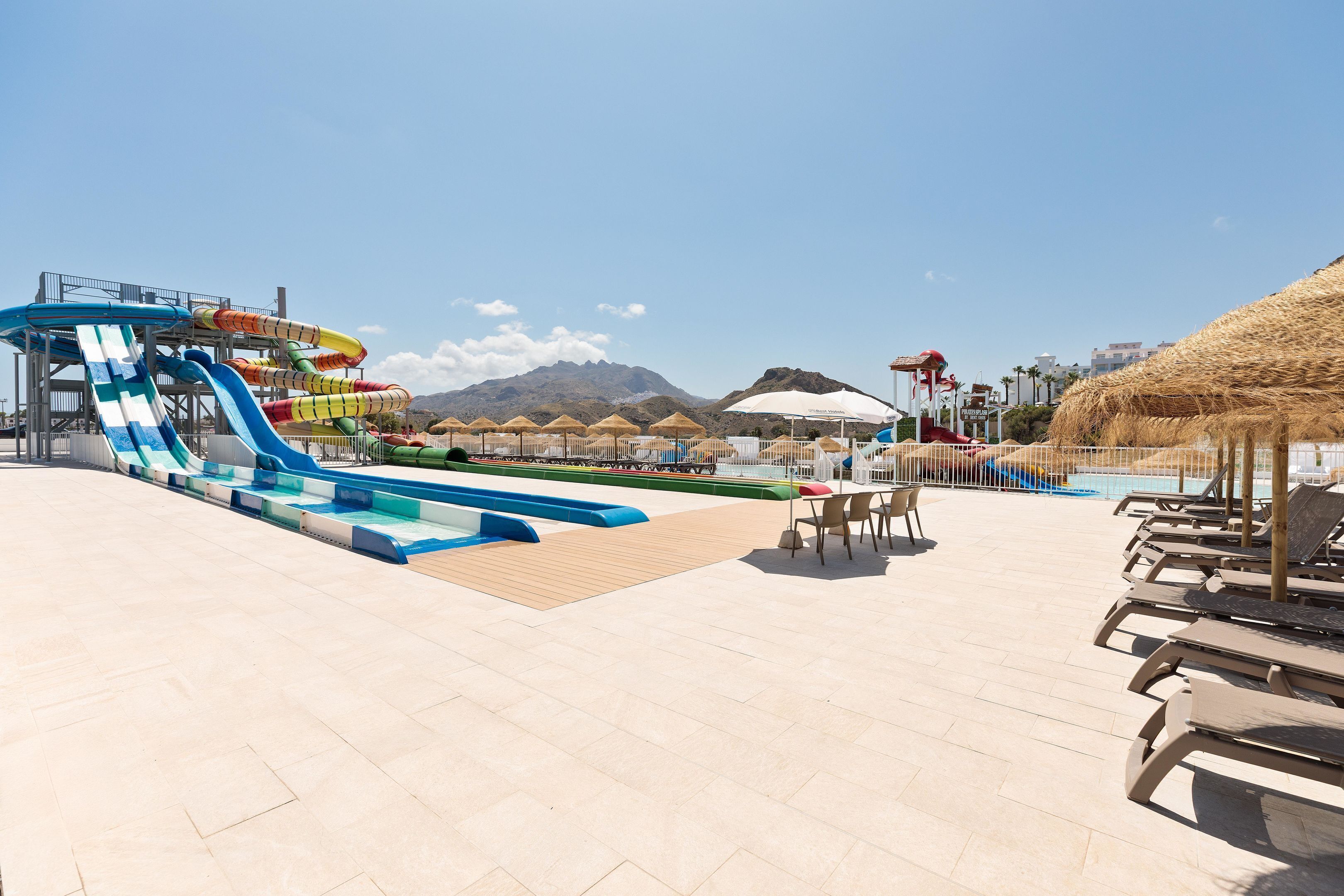 A water park with multiple slides and a pool area with lounge chairs and umbrellas.