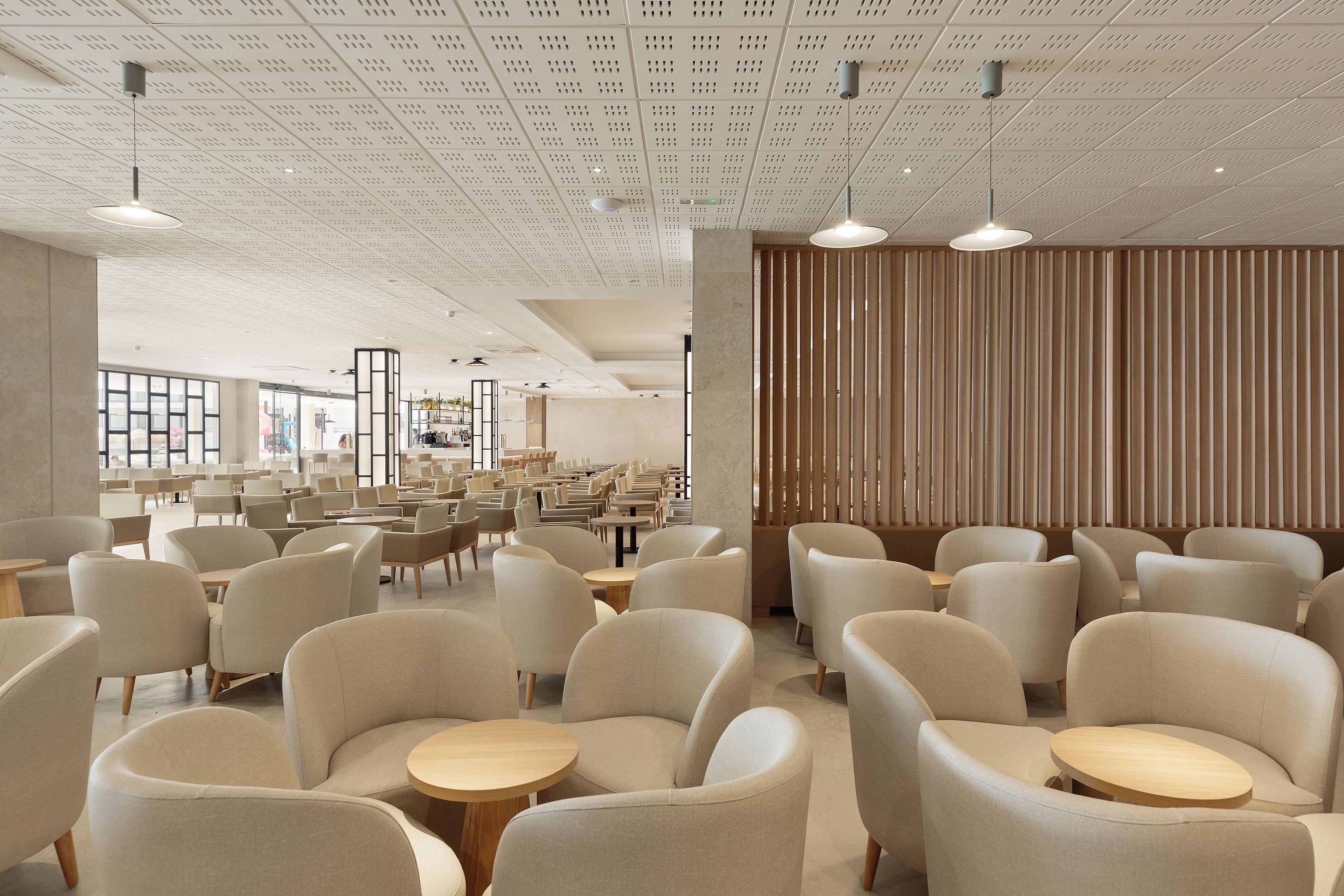 A modern interior with numerous seating areas, a patterned ceiling, and a wooden partition wall.