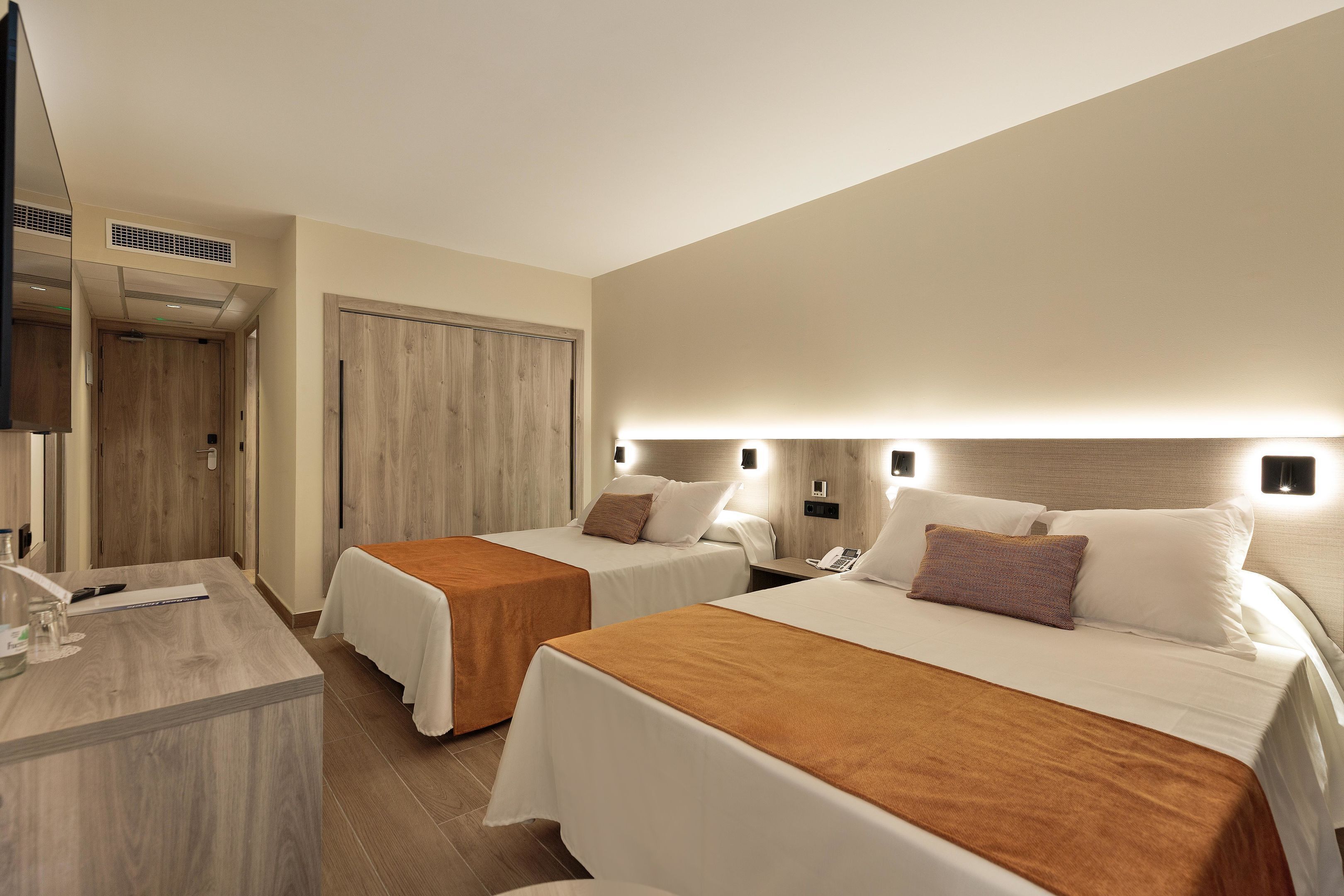 Una habitación de hotel con dos camas, un escritorio y una televisión.