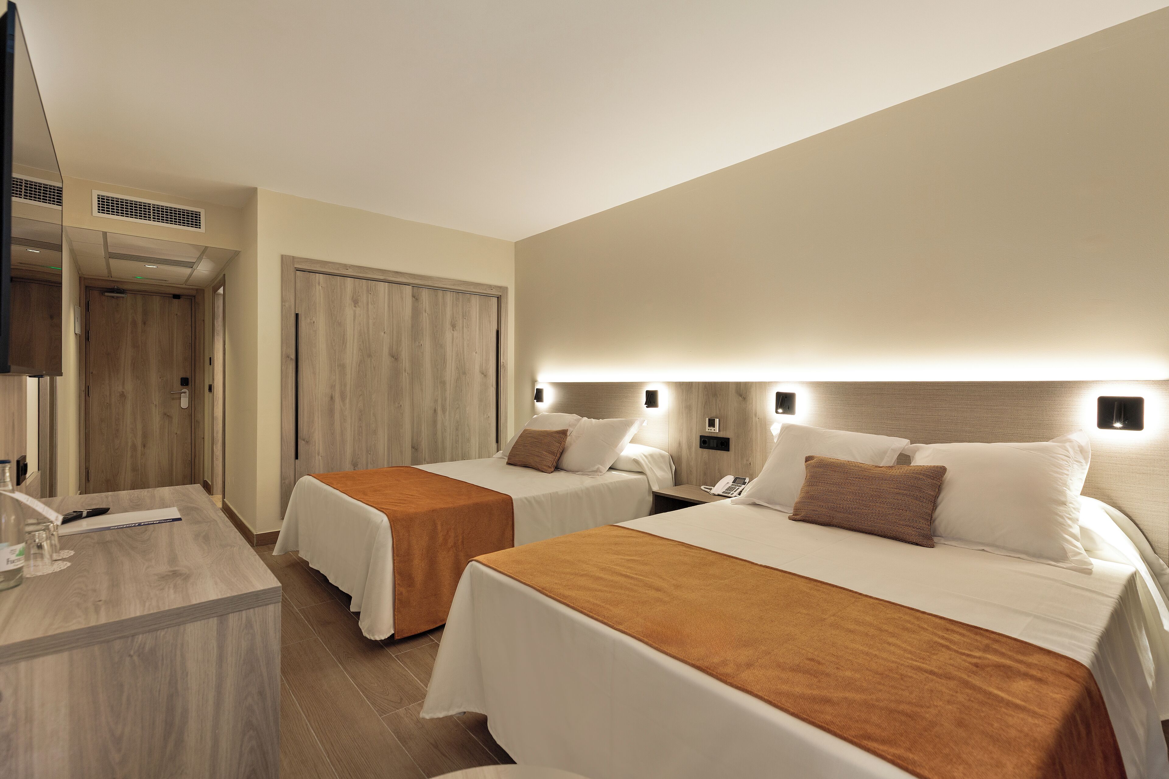 Habitación de hotel con dos camas, un escritorio y una televisión.