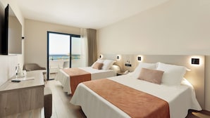 Habitación de hotel con dos camas, un escritorio, una silla, televisión y vista al mar.