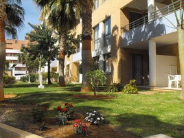 Un patio de hotel con palmeras, césped y un parterre de flores.