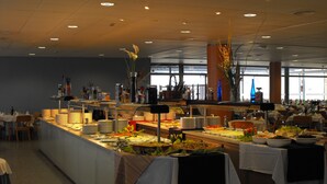 A buffet setup with various food items and utensils, tables covered with white tablecloths, and a ceiling with recessed lighting. - Neptuno (Roquetas de Mar)