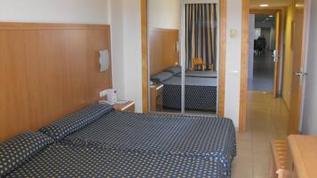 Ein Hotelzimmer mit einem großen Bett, einem Holz-Kopfteil, einem Nachttisch mit Lampe und einem Spiegel.