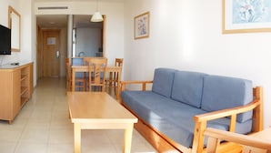 Een woonkamer met een bank, een houten tafel, een televisie en een keuken op de achtergrond.
