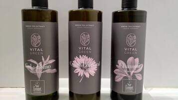 Three bottles of Vital Green hair care products on a white shelf.